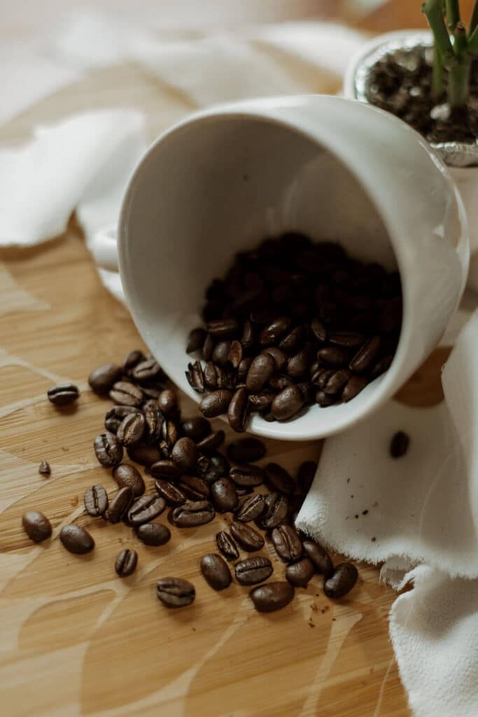 coffee beans spilling out of a white mug