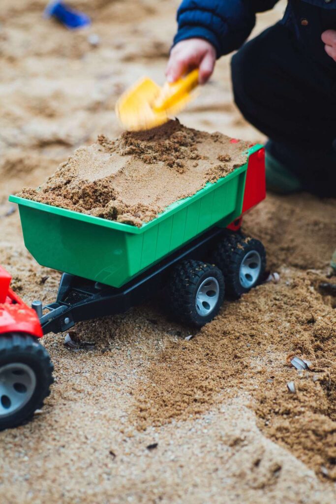 toddler playing with a dump truck in the sand
