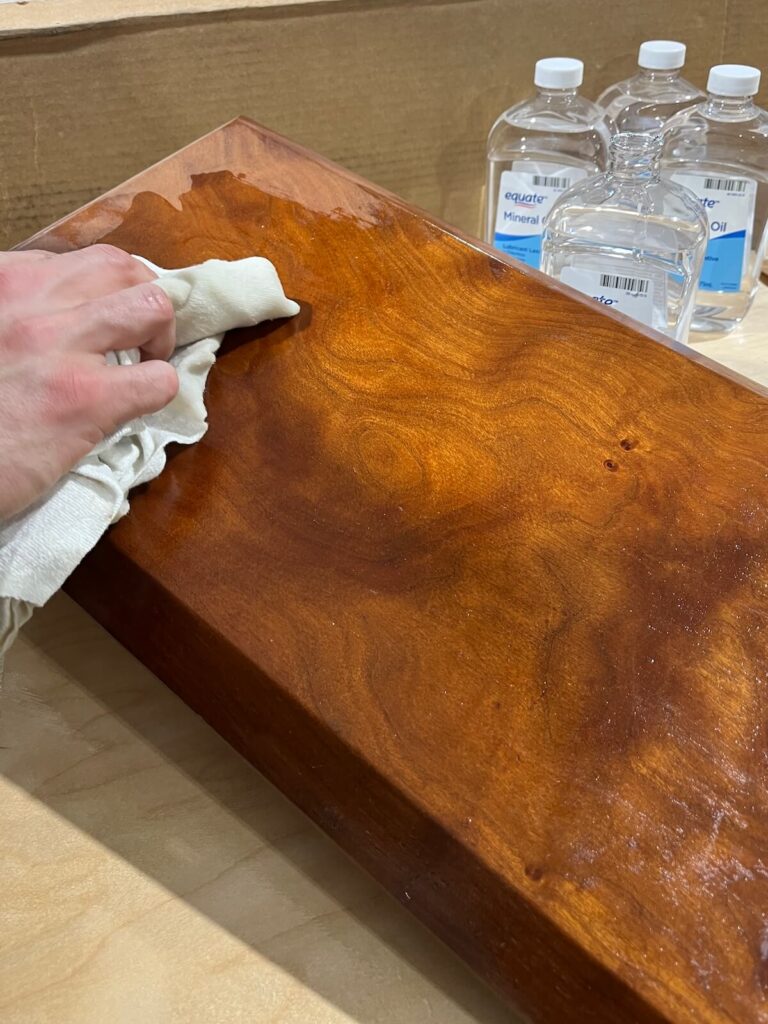 wiping oil on the back of a charcuterie board