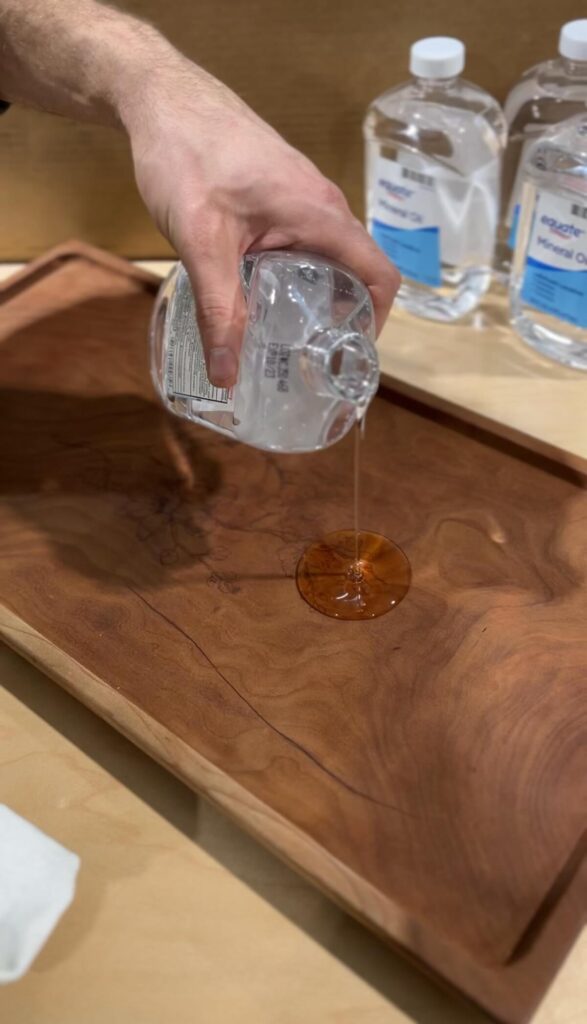 hand pouring mineral oil on a charcuterie board