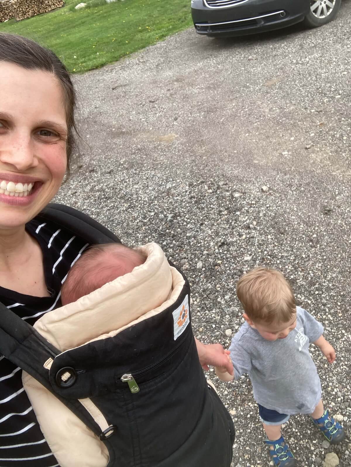 mom with baby in ergobaby carrier holding toddlers hand