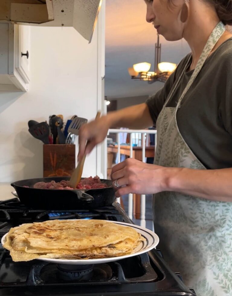 woman wearing apron cooking beef on stove