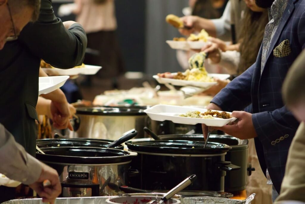 hands getting food over table at church potluck
