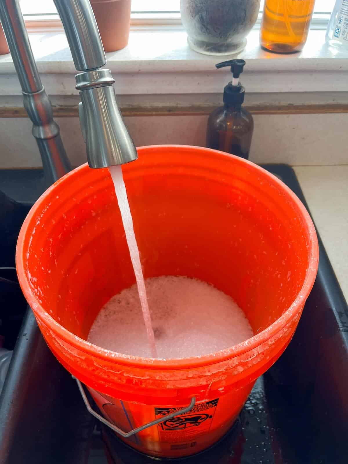 filling 5-gallon bucket with water for homemade laundry detergent