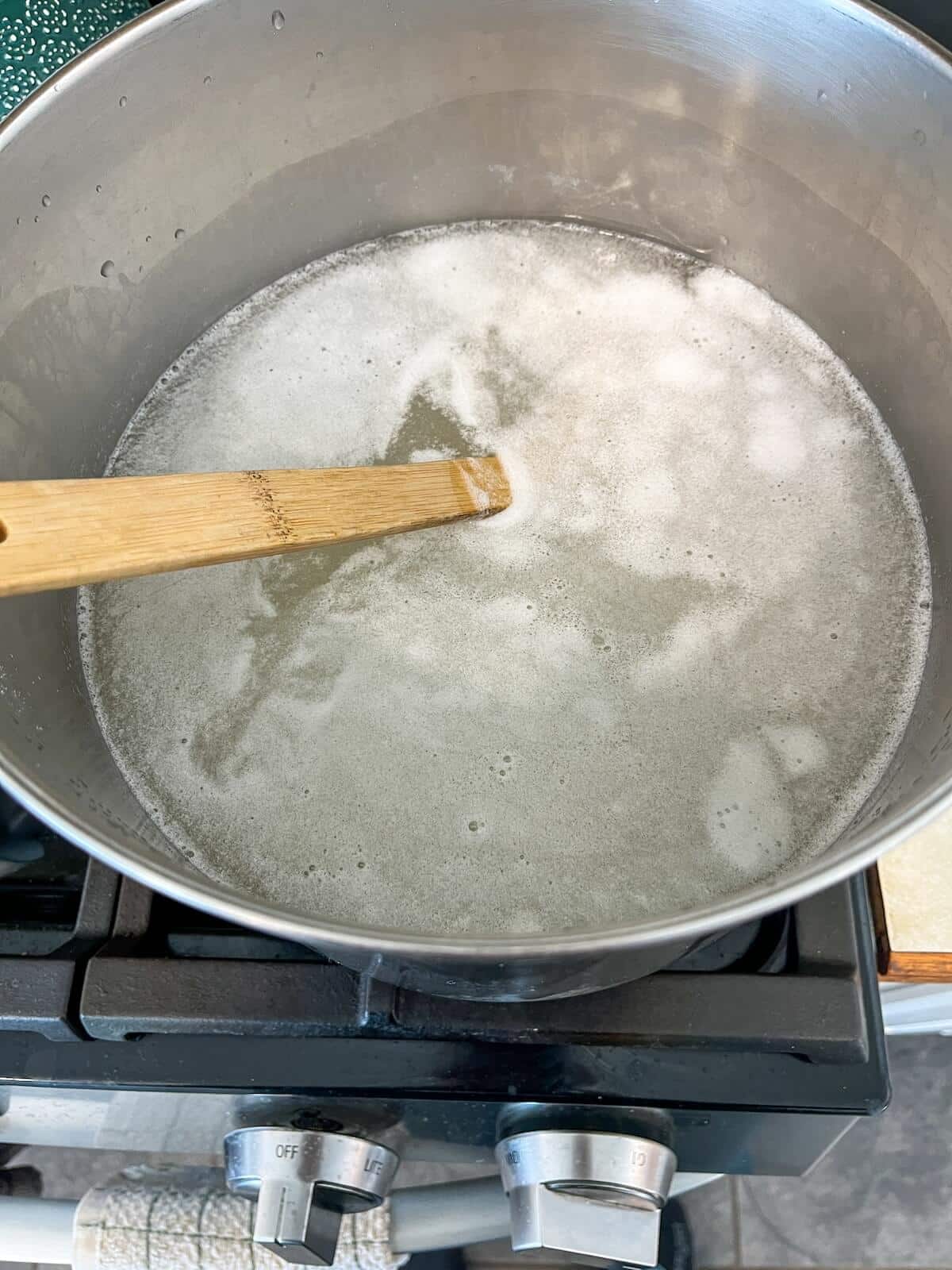 stirring borax washing soda and castile soap in pot for homemade laundry detergent