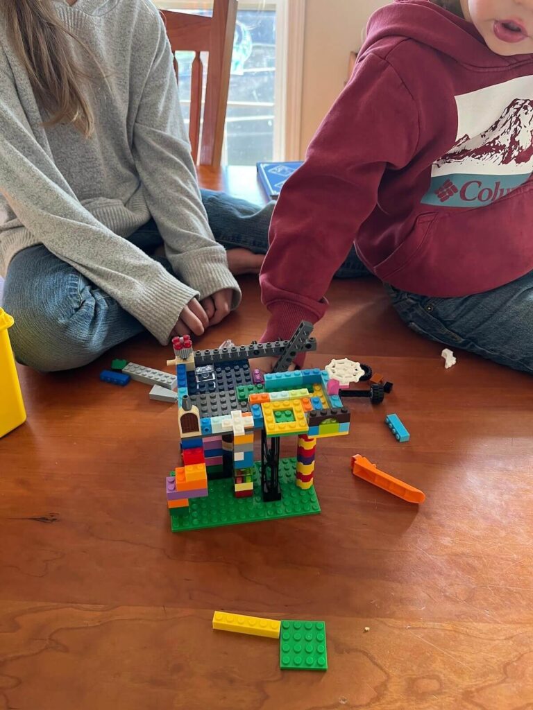 two kids sitting at table making lego creation