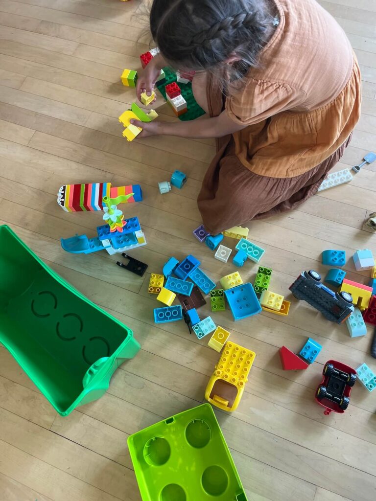 young girl in dress on floor playing lego duplos